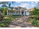 Charming home with a spacious front porch, brick driveway, and lush landscaping, set against a blue sky at 1100 Cordova Ne Blvd, St Petersburg, FL 33704