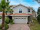 Charming two-story home with a terracotta roof, brick driveway, and lush tropical landscaping at 1259 Ribolla Dr, Palm Harbor, FL 34683