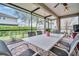 Screened patio area with brick flooring, ceiling fan, dining set, and view of the landscaped yard at 1259 Ribolla Dr, Palm Harbor, FL 34683