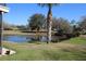 View of pond with bridge, grassy yard and mature trees at 130 Water Oak Way, Oldsmar, FL 34677