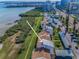 Aerial view of townhomes near a waterfront with lush vegetation along the coast and a road with light traffic at 1451 Gulf Blvd # 207, Clearwater Beach, FL 33767