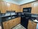 Bright kitchen with wooden cabinets, black countertops, and stainless steel appliances at 204 Pine Tulip Ct # 102, Tampa, FL 33612
