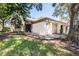 Charming single-story home with well-manicured lawn and attached garage, nestled under mature trees at 2201 Pine Dr, Tarpon Springs, FL 34689