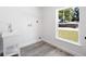 Bright laundry room features a utility sink, window view, wood-look gray flooring, and white walls at 23 N Edwards St, Plant City, FL 33563