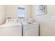 Well-lit laundry room featuring modern, white, front-loading washer and dryer units at 3501 Rosewood Ramble Ct, Plant City, FL 33565