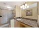 Bright bathroom featuring a granite countertop, modern vanity, decorative mirror, and glass enclosed shower at 6268 Palma Del Mar S Blvd # 113, St Petersburg, FL 33715