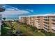 Exterior of a multi-story building with balconies overlooking a manicured lawn and a beachside view on a sunny day at 6500 Sunset Way # 501, St Pete Beach, FL 33706