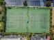 Aerial view of four well-maintained community tennis courts with lush green surroundings and a parking lot at 6500 Sunset Way # 501, St Pete Beach, FL 33706