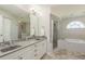 Bright bathroom features dual sinks, large mirror, soaking tub, and glass shower at 6705 Myrna Dr, Tampa, FL 33619