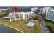 Aerial view of condo building featuring pool, covered parking, and waterfront location at 100 Oakmont Ln # 605, Belleair, FL 33756