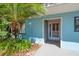 Inviting front entrance with a decorative palm tree and number plate on a bright blue building exterior at 104 Anclote Rd # 104, Tarpon Springs, FL 34689