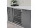Close-up of the stylish grey wet bar with a white countertop and beverage cooler at 11266 Kapok Grand Cir, Madeira Beach, FL 33708