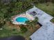Aerial view of a community pool featuring ample seating, lush landscaping and a nearby recreational center at 11266 Kapok Grand Cir, Madeira Beach, FL 33708