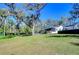 Large backyard features mature trees and partial view of home, patio and in-ground pool at 11524 River Country Dr, Riverview, FL 33569