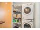 Efficient laundry area featuring a stacked washer and dryer unit with ample shelving for storage and organization at 12709 Raeburn Way, Tampa, FL 33624