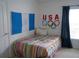 Cozy bedroom with a striped bedspread and flags displayed on the wall at 19432 Haskell Pl, Land O Lakes, FL 34638