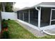 Enclosed, screened porch with a view of a white fence, an adjacent stone trim and green backyard at 19432 Haskell Pl, Land O Lakes, FL 34638