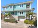 Coastal home featuring light blue siding, white trim, balconies, and lush landscaping for curb appeal at 30 79Th Ave, Treasure Island, FL 33706