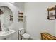 Charming half-bathroom with a pedestal sink, a round mirror, and decorative wall shelves for storage and decor at 34159 Astoria Cir, Wesley Chapel, FL 33545