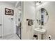 Stylish half-bathroom with a pedestal sink, an oval mirror, and patterned towels, leading to a hallway at 34159 Astoria Cir, Wesley Chapel, FL 33545