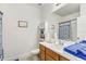 Neutral bathroom featuring a white sink, wood cabinet and a tub with blue shower curtain at 34159 Astoria Cir, Wesley Chapel, FL 33545