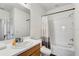 Bright bathroom featuring a white sink, wood cabinet and a tub with white tile surround at 34159 Astoria Cir, Wesley Chapel, FL 33545