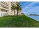 Beautiful condo building featuring lush green lawn, palm trees and waterfront views at 4525 Cove Cir # 705, St Petersburg, FL 33708