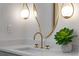 Close-up of bathroom vanity with gold faucet, artistic mirror, and decorative succulent at 4568 40Th S St, St Petersburg, FL 33711
