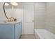 Bathroom featuring blue vanity with speckled countertop, round mirror, tub and wood-look flooring at 4568 40Th S St, St Petersburg, FL 33711