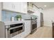 Gourmet kitchen featuring white cabinets, stainless appliances including oven, and a stylish blue tile backsplash at 4568 40Th S St, St Petersburg, FL 33711