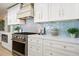 Elegant kitchen with white cabinetry, stainless steel appliances, light wood floors and blue tiled backsplash at 4568 40Th S St, St Petersburg, FL 33711