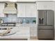 Bright kitchen featuring white cabinetry, stainless steel appliances, and stylish blue tile backsplash at 4568 40Th S St, St Petersburg, FL 33711