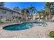 The community pool is surrounded by palm trees, a brick patio, and white fencing at 5162 Sunridge Palms Dr # 5162, Tampa, FL 33617
