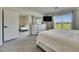 Bright bedroom with white furniture, TV, large window overlooking grassy lawn, and an open doorway to a sitting room at 5617 Flagstone Trl, Palmetto, FL 34221