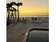 Tropical backyard featuring palm trees, tables, chairs, and ocean views at sunset at 712 Beach Trl # C, Indian Rocks Beach, FL 33785