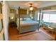 Comfortable bedroom with a four-poster bed, ceiling fan and seating area by the window at 712 Beach Trl # C, Indian Rocks Beach, FL 33785