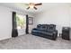 This bedroom features gray walls, a ceiling fan, a gray carpeted floor, and a comfortable black leather sofa at 7352 Cutwater Ln, Wesley Chapel, FL 33545