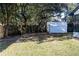 A fenced backyard features grass, mature trees, and a white storage shed at 8436 Cameo St, Spring Hill, FL 34608