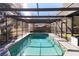 An in-ground screened pool is surrounded by patio and mature trees at 8436 Cameo St, Spring Hill, FL 34608