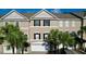 Charming townhome showcasing three-story facade, arched windows, an attached garage, and mature landscaping at 14 Seagrape Cir, Clearwater, FL 33759