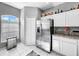 Bright kitchen boasts granite countertops, stainless steel refrigerator, and white tile flooring at 14 Seagrape Cir, Clearwater, FL 33759