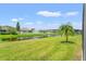 Picturesque backyard with pond view, complemented by a mature palm tree and green lawn at 12524 25Th E Ct, Parrish, FL 34219