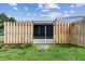 View of a fenced backyard with a concrete patio area and a screen door at 211 Somerset Cirle N, Dunedin, FL 34698