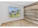 Bedroom with wood accent wall, window, and wood flooring at 211 Somerset Cirle N, Dunedin, FL 34698