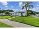 Charming single-story home with a well-manicured lawn and a beautiful palm tree in a tranquil neighborhood at 211 Somerset Cirle N, Dunedin, FL 34698