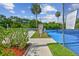 Outdoor tennis court with net, fencing, signage, benches and palm trees in the background at 211 Somerset Cirle N, Dunedin, FL 34698