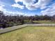 A spacious, grassy backyard is bordered by a white fence and a river beyond at 3150 Marine Grass Dr, Wimauma, FL 33598
