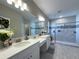 Bathroom featuring double vanity, white cabinets, large mirror, and tiled floors and backsplash at 3150 Marine Grass Dr, Wimauma, FL 33598