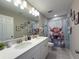 The bathroom with double sinks showcases a decorative shower curtain and matching artwork at 3150 Marine Grass Dr, Wimauma, FL 33598