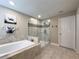 A relaxing bathroom includes a soaking tub and walk-in shower with neutral tiling at 3150 Marine Grass Dr, Wimauma, FL 33598